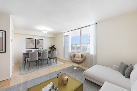 A living room with a grey couch, a grey chair, a grey dining table and chairs, a grey rug, a yellow coffee table, and a painting on the wall.